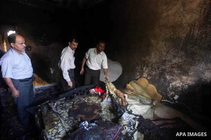 Palestinians inspect the damage in the bedroom of one-year-old Fathi Baghdadi, who died after a fire from a candle that swept through their home in the Bureij refugee camp in the center of the Gaza Strip on September 26,...