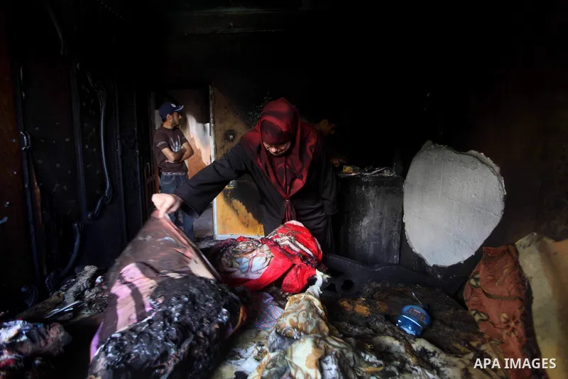Palestinians inspect the damage in the bedroom of one-year-old Fathi Baghdadi, who died after a fire from a candle that swept through their home in the Bureij refugee camp in the center of the Gaza Strip on September 26,...