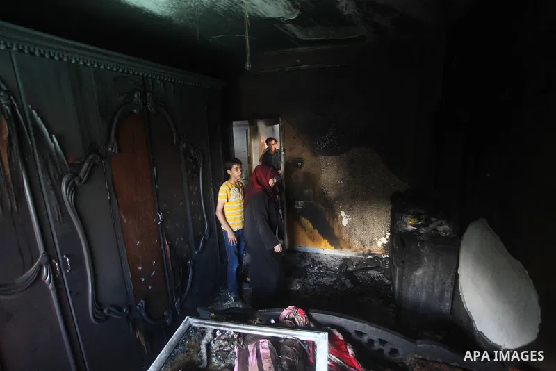 Palestinians inspect the damage in the bedroom of one-year-old Fathi Baghdadi, who died after a fire from a candle that swept through their home in the Bureij refugee camp in the center of the Gaza Strip on September 26,...