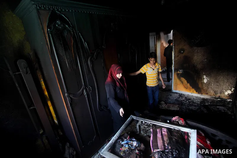 Palestinians inspect the damage in the bedroom of one-year-old Fathi Baghdadi, who died after a fire from a candle that swept through their home in the Bureij refugee camp in the center of the Gaza Strip on September 26,...