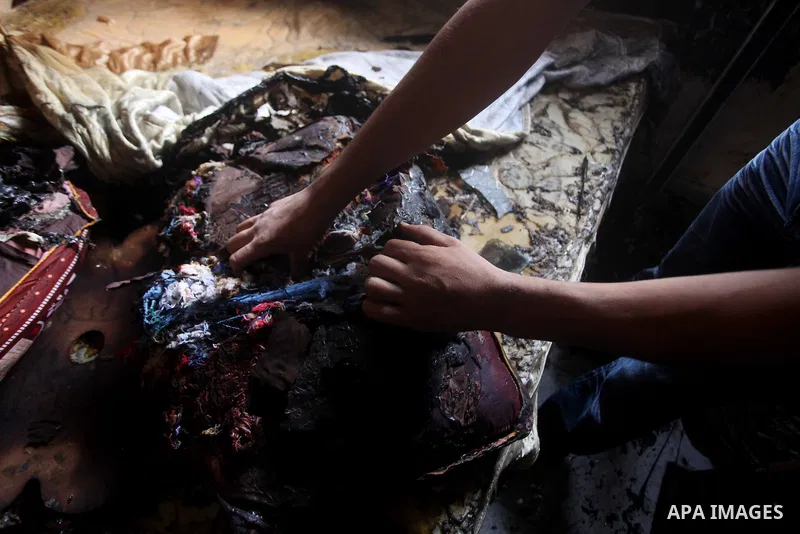 Palestinians inspect the damage in the bedroom of one-year-old Fathi Baghdadi, who died after a fire from a candle that swept through their home in the Bureij refugee camp in the center of the Gaza Strip on September 26,...
