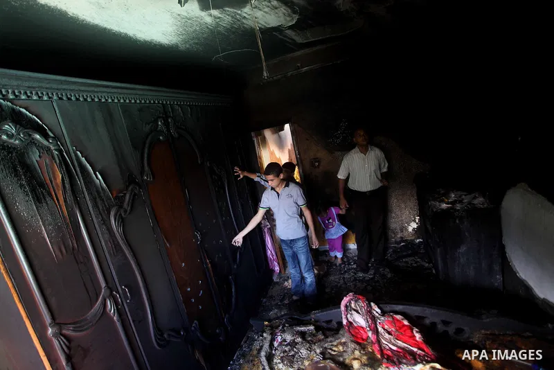 Palestinians inspect the damage in the bedroom of one-year-old Fathi Baghdadi, who died after a fire from a candle that swept through their home in the Bureij refugee camp in the center of the Gaza Strip on September 26,...
