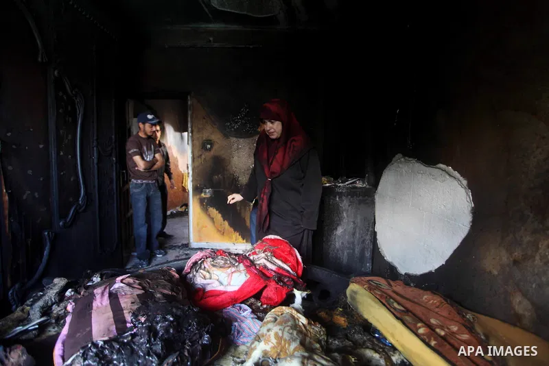 Palestinians inspect the damage in the bedroom of one-year-old Fathi Baghdadi, who died after a fire from a candle that swept through their home in the Bureij refugee camp in the center of the Gaza Strip on September 26,...