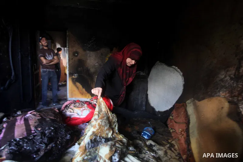 Palestinians inspect the damage in the bedroom of one-year-old Fathi Baghdadi, who died after a fire from a candle that swept through their home in the Bureij refugee camp in the center of the Gaza Strip on September 26,...