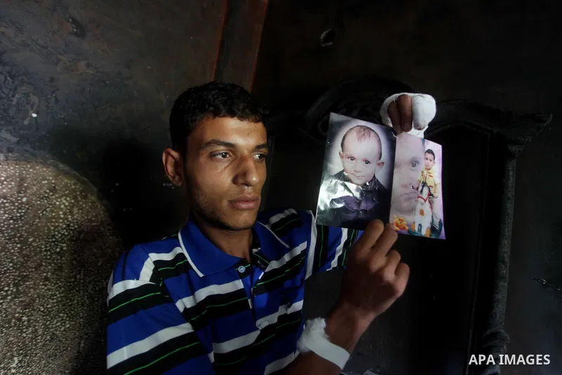 A Palestinian father hold picture a photograph of one-year-old Fathi Baghdadi, who died after a fire from a candle that swept through their home in the Bureij refugee camp in the center of the Gaza Strip on September 26,...