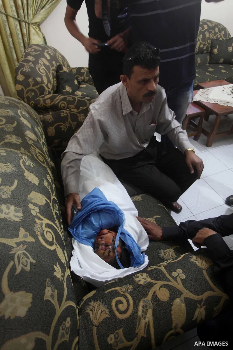 Palestinian mourners carry the body of three-year-old Fathi Baghdadi, who was killed in an overnight domestic fire, lies on a couch at his home in the Bureij refugee camp, centeral Gaza Strip, on September 26, 2012. The...