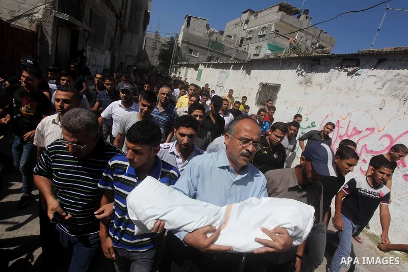 Palestinian mourners carry the body of three-year-old Fathi Baghdadi, who was killed in an overnight domestic fire, lies on a couch at his home in the Bureij refugee camp, centeral Gaza Strip, on September 26, 2012. The...