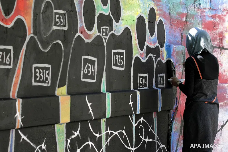 A Palestinian artist draws a graffiti in front of the red cross office during a ceremony to support the prisoners in Israeli jails, in Gaza city on 26 September 2012. Photo by Majdi Fathi