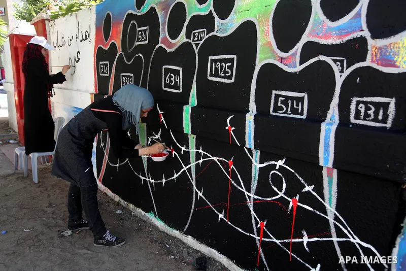 Palestinian artists draw a graffiti in front of the red cross office during a ceremony to support the prisoners in Israeli jails, in Gaza city on 26 September 2012. Photo by Majdi Fathi