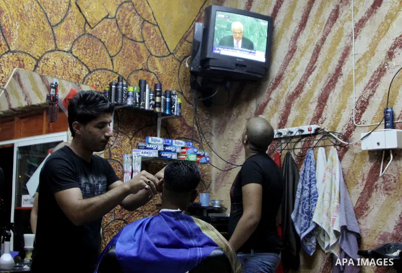 Palestinians watch TV during the speech of Palestinian President Mahmoud Abbas at the at UN headquarters in New York in the 67th session of the United Nations General Assembly, at a coiffure shop in the West Bank city of...