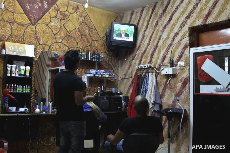 Palestinians watch TV during the speech of Palestinian President Mahmoud Abbas at the at UN headquarters in New York in the 67th session of the United Nations General Assembly, at a coiffure shop in the West Bank city of...