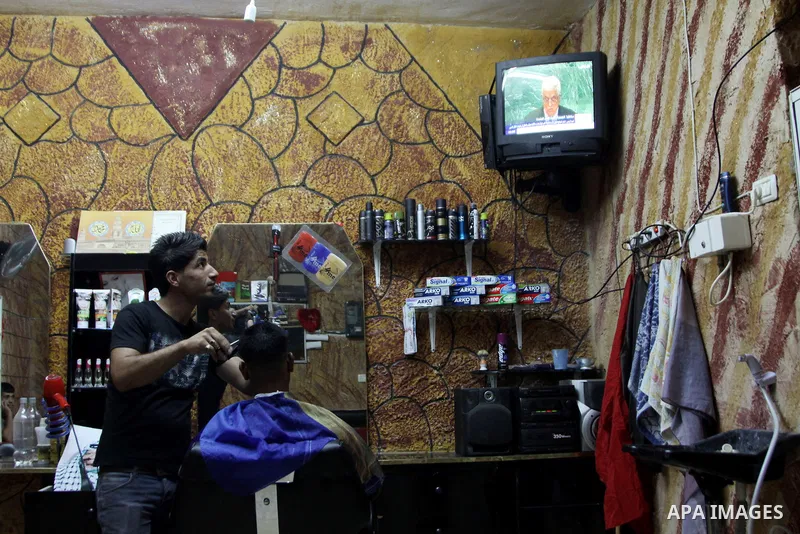 Palestinians watch TV during the speech of Palestinian President Mahmoud Abbas at the at UN headquarters in New York in the 67th session of the United Nations General Assembly, at a coiffure shop in the West Bank city of...