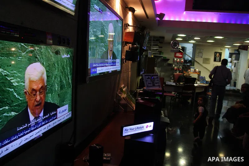 Palestinians walk past a shop during the speech of Palestinian President Mahmoud Abbas at the at UN headquarters in New York in the 67th session of the United Nations General Assembly, in the West Bank city of Ramallah o...