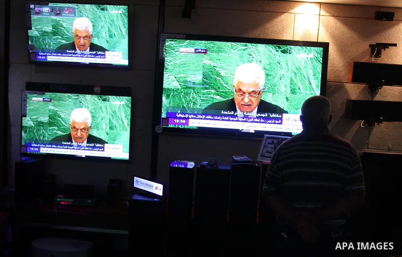 Palestinians walk past a shop during the speech of Palestinian President Mahmoud Abbas at the at UN headquarters in New York in the 67th session of the United Nations General Assembly, in the West Bank city of Ramallah o...