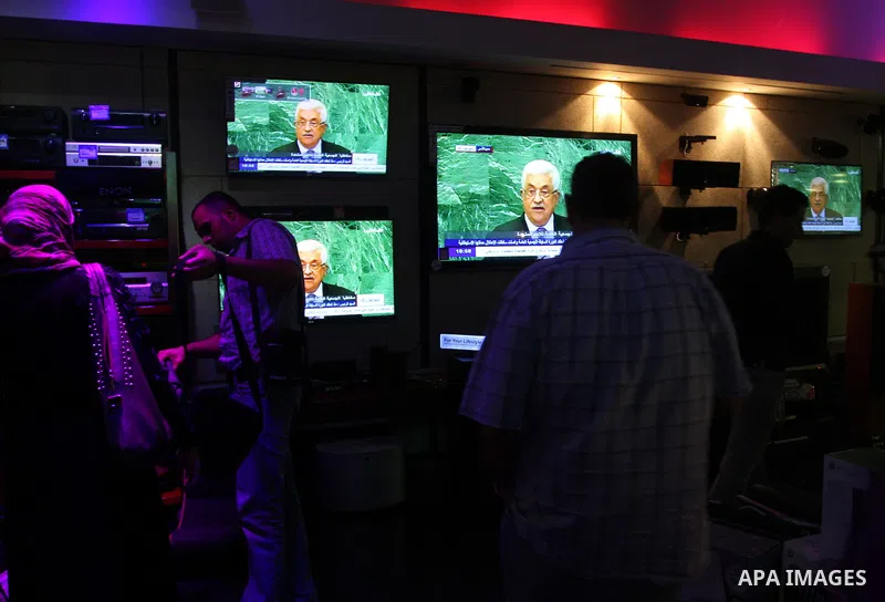 Palestinians walk past a shop during the speech of Palestinian President Mahmoud Abbas at the at UN headquarters in New York in the 67th session of the United Nations General Assembly, in the West Bank city of Ramallah o...