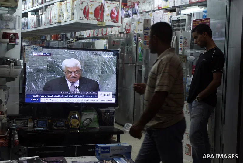 Palestinians walk past a shop during the speech of Palestinian President Mahmoud Abbas at the at UN headquarters in New York in the 67th session of the United Nations General Assembly, in the West Bank city of Ramallah o...