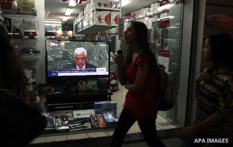Palestinians walk past a shop during the speech of Palestinian President Mahmoud Abbas at the at UN headquarters in New York in the 67th session of the United Nations General Assembly, in the West Bank city of Ramallah o...