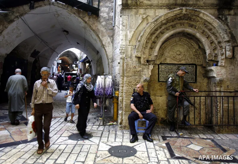 Palestinians walk past Israeli police at the market in Jerusalem's old city on 27 September 2012. Photo by Mahfouz Abu Turk