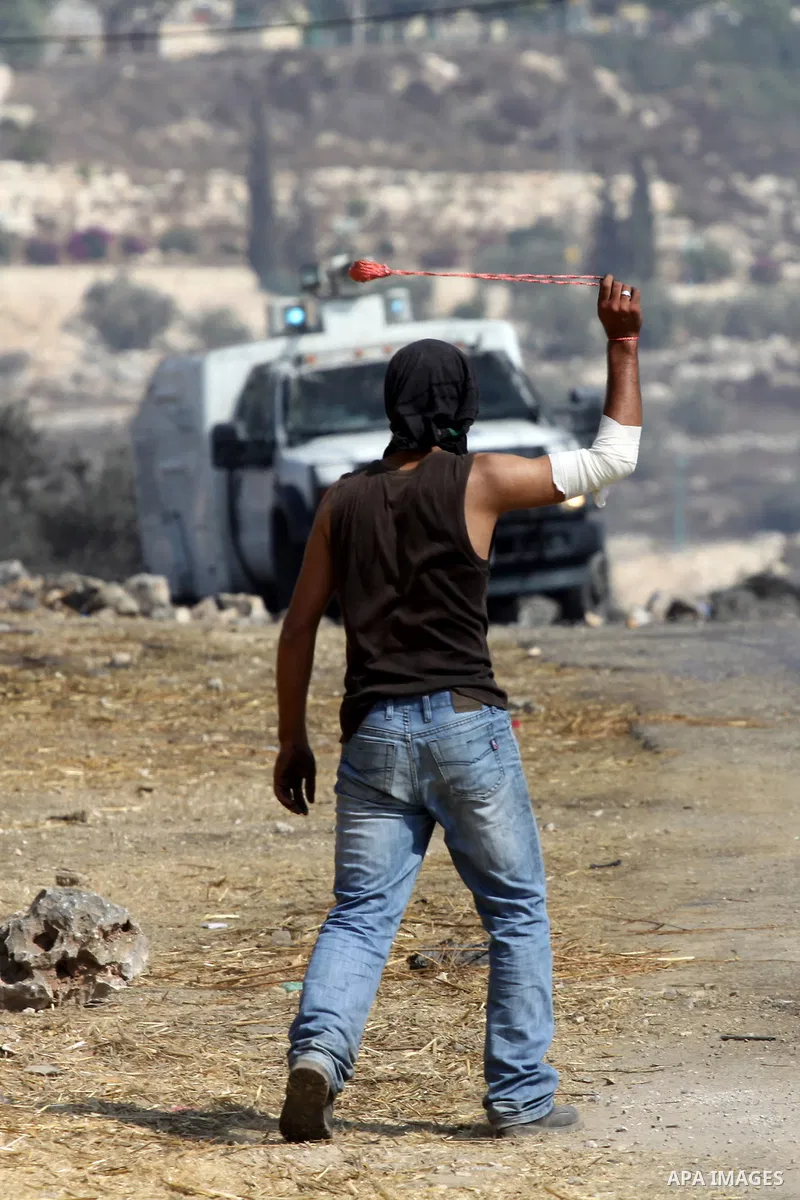 A Palestinian protester throws stones at Israeli troops after a demonstration against the expropriation of Palestinian land by Israel in the village of Kfar Qaddum, near the West Bank city of Nablus, on september 28, 201...