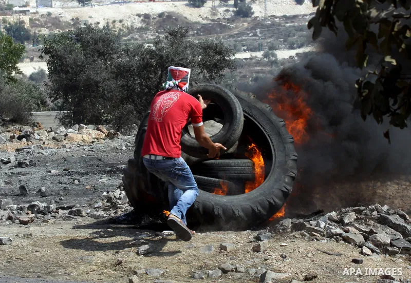 A Palestinian protester burns tires after a demonstration against the expropriation of Palestinian land by Israel in the village of Kfar Qaddum, near the West Bank city of Nablus, on september 28, 2012. Photo by Nedal Es...