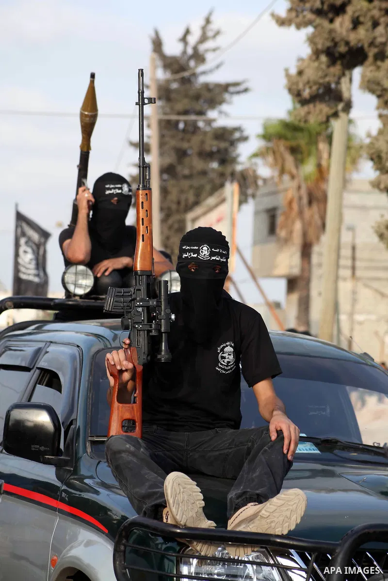 Palestinian militants from the Al Nasser Brigades, an armed wing of the Popular Resistance Committees (PRC) hold weapons during a rally marking the 12th anniversary of the brigades, in Gaza city, Friday, Sept. 28, 2012....