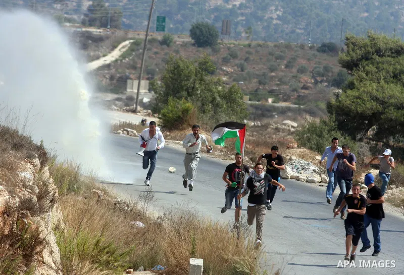 Palestinian protesters run away from a water canon used by Israeli troops to disperse protesters during a weekly protest against the expansion of the nearby Jewish settlement of Halamish, in the West Bank village of Nabi...