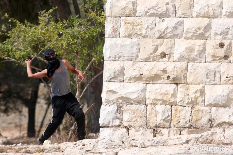 A Palestinian protester hurls stones at Israeli soldiers during a weekly protest against the expansion of the nearby Jewish settlement of Halamish, in the West Bank village of Nabi Saleh near Ramallah, Friday, Sept 28, 2...
