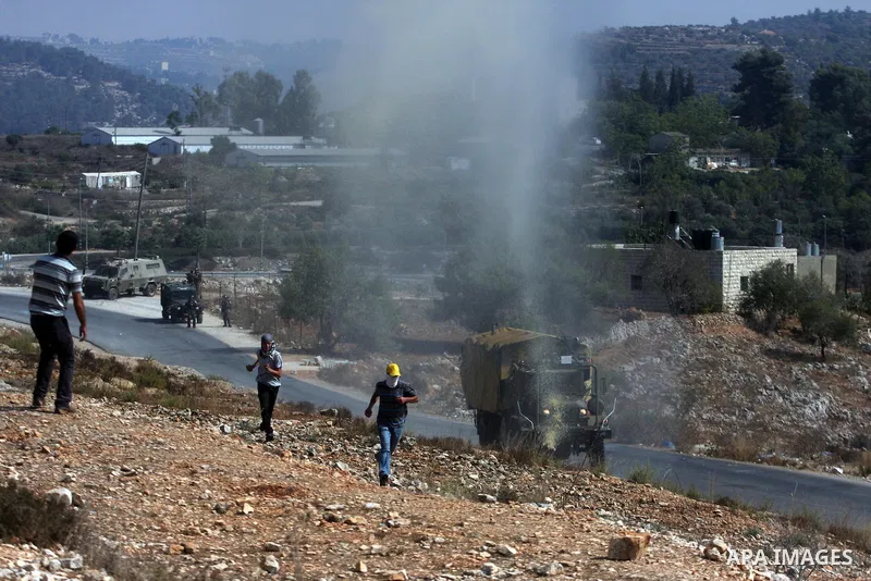 Palestinian protesters run away from a water canon used by Israeli troops to disperse protesters during a weekly protest against the expansion of the nearby Jewish settlement of Halamish, in the West Bank village of Nabi...