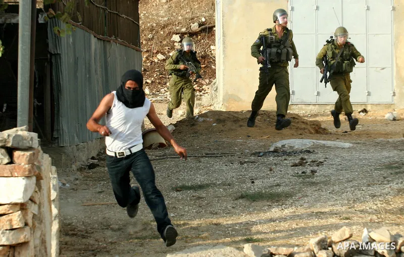 Israeli soldiers run follow Palestinian protesters after a demonstration against the expropriation of Palestinian land by Israel in the village of Kfar Qaddum, near the West Bank city of Nablus,Palestinian protesters thr...
