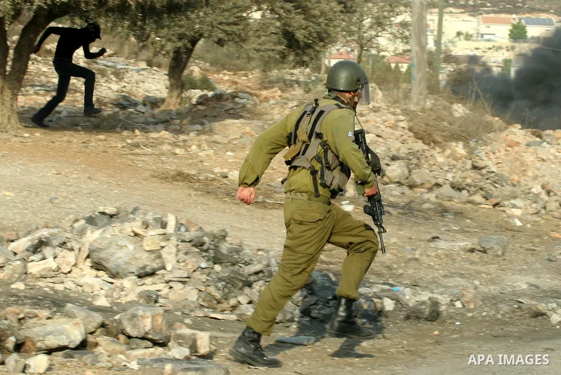 A Israeli soldiers run follow Palestinian protesters after a demonstration against the expropriation of Palestinian land by Israel in the village of Kfar Qaddum, near the West Bank city of Nablus,Palestinian protesters t...