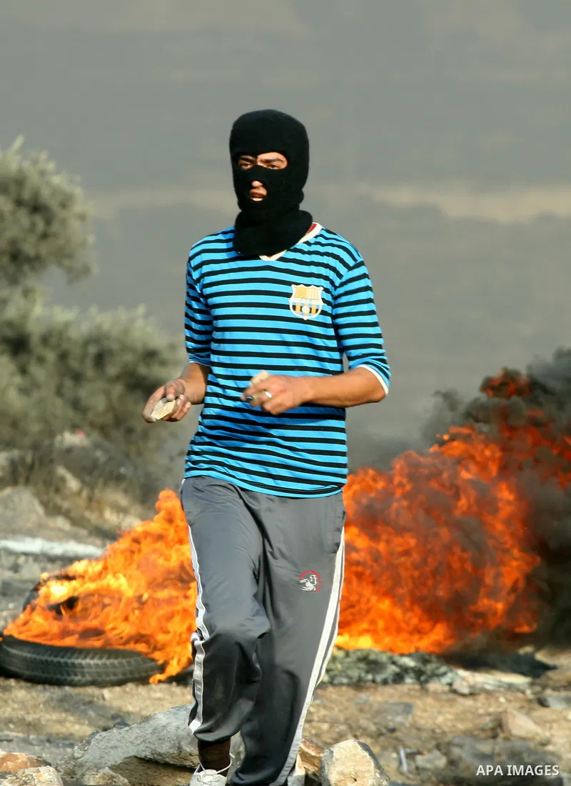 A Palestinian protester throw stones at Israeli troops after a demonstration against the expropriation of Palestinian land by Israel in the village of Kfar Qaddum, near the West Bank city of Nablus, in support of Palesti...