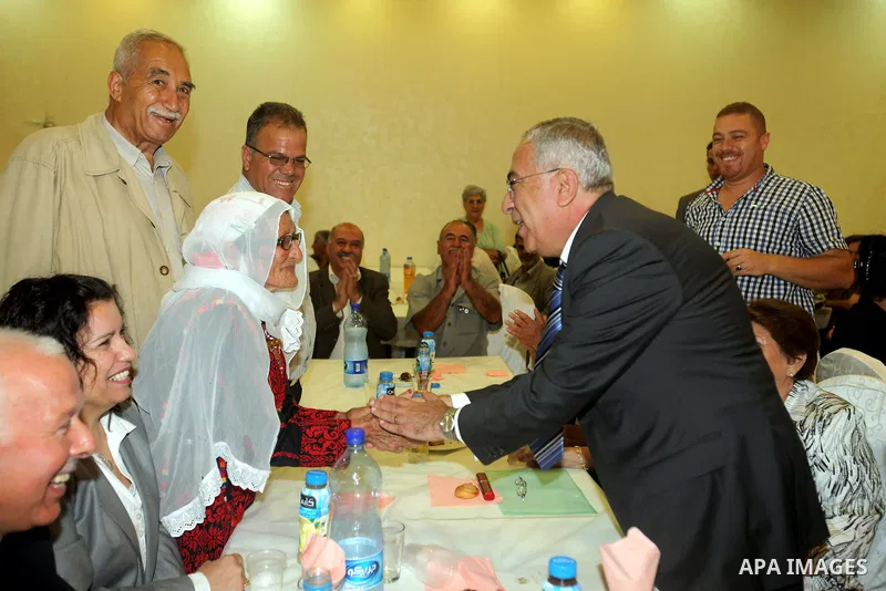 Palestinian Prime Minister Salam Fayyad shakes hands with an elderly woman during the the ceremony of The International Day of Older Persons in the West Bank city of Ramallah on October 1, 2012. The Day of Older Persons...