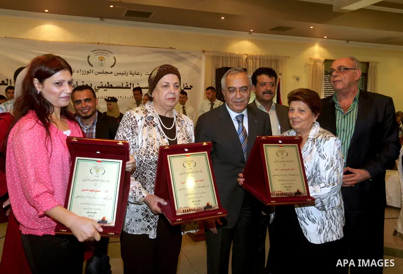 Palestinian Prime Minister Salam Fayyad honors elderly women during the the ceremony of the International Day of Older Persons in the West Bank city of Ramallah on October 1, 2012. The Day of Older Persons is celebrated...