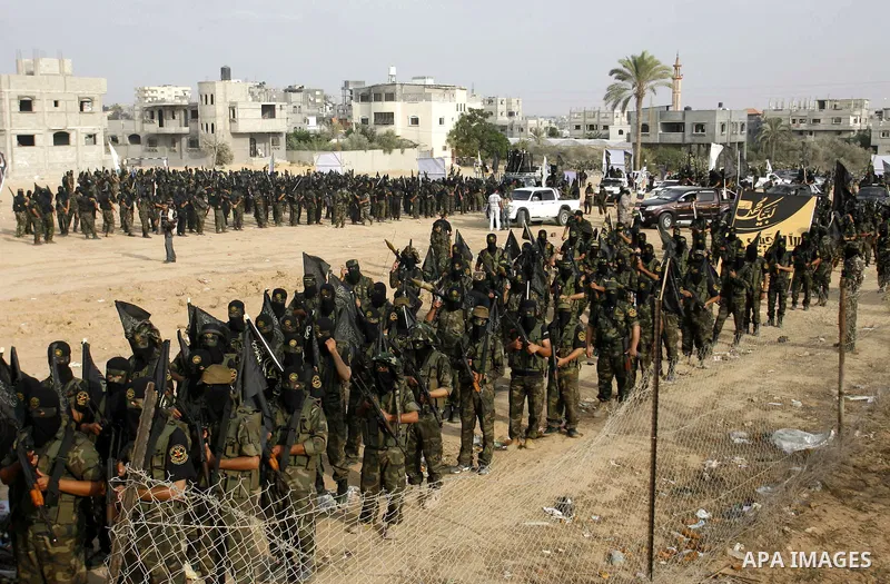 Palestinian militants from the Islamic Jihad, an armed wing of the Al-Quds Brigades hold weapons during a rally marking the 25th anniversary of the Jihad movement's establishment in Rafah in the southern Gaza Strip on Oc...