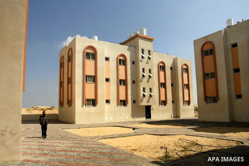 Palestinians walk in front of their new houses in a project funded by the United Nations Relief and Works Agency for Palestine Refugees (UNRWA) in Rafah, in the southern of Gaza Strip on Oct. 03, 2012. Palestinians whose...