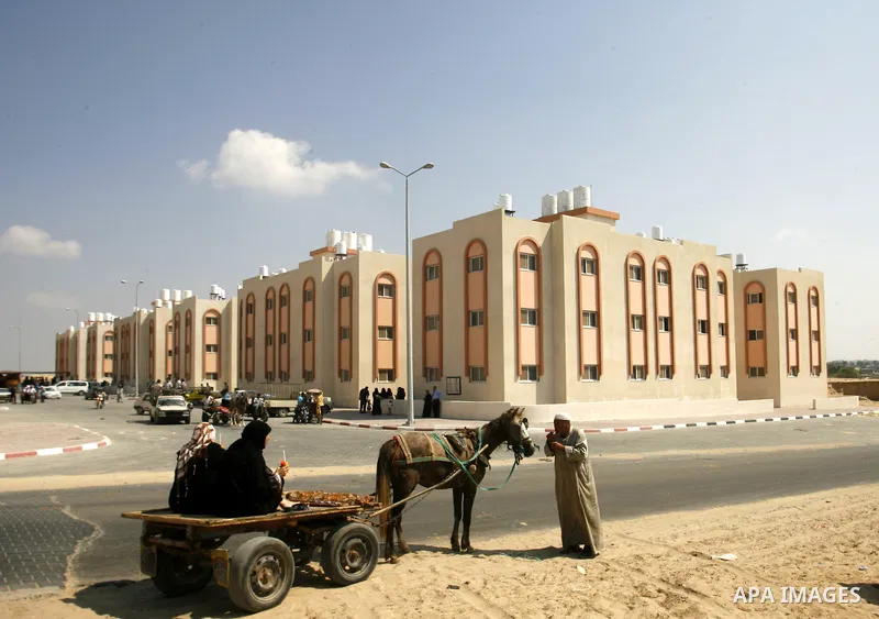 Palestinians walk in front of their new houses in a project funded by the United Nations Relief and Works Agency for Palestine Refugees (UNRWA) in Rafah, in the southern of Gaza Strip on Oct. 03, 2012. Palestinians whose...