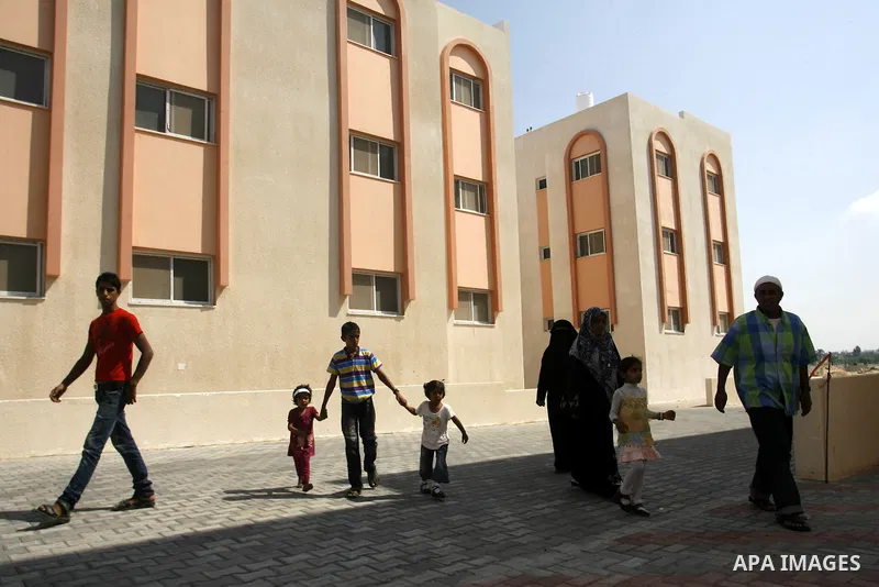 Palestinians walk in front of their new houses in a project funded by the United Nations Relief and Works Agency for Palestine Refugees (UNRWA) in Rafah, in the southern of Gaza Strip on Oct. 03, 2012. Palestinians whose...