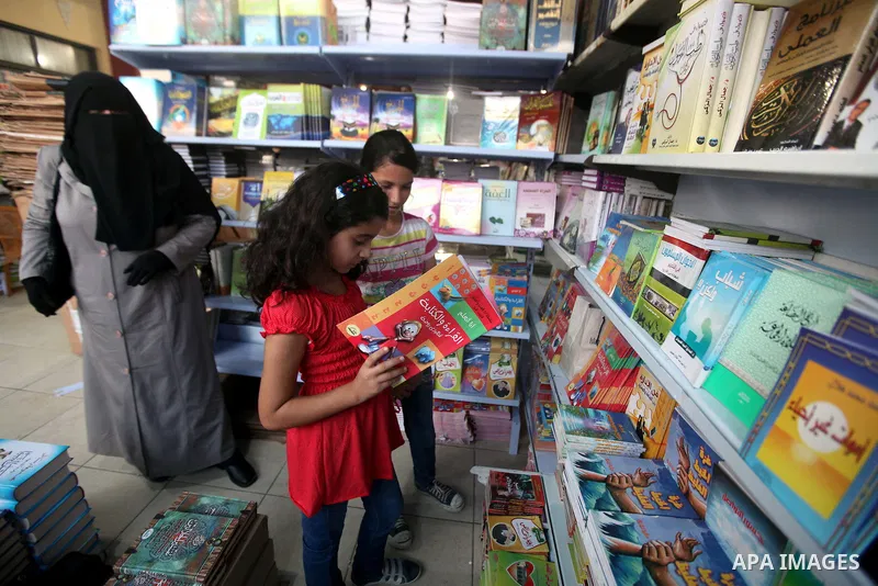 Palestinian visitors read books at a booth during the launch of the International Book Fair Exhibition, in Gaza city , Oct. 03, 2012. The Gaza International Book Fair has participated with more than 70 publishers from Pa...