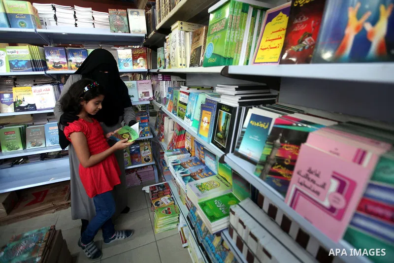 Palestinian visitors read books at a booth during the launch of the International Book Fair Exhibition, in Gaza city , Oct. 03, 2012. The Gaza International Book Fair has participated with more than 70 publishers from Pa...