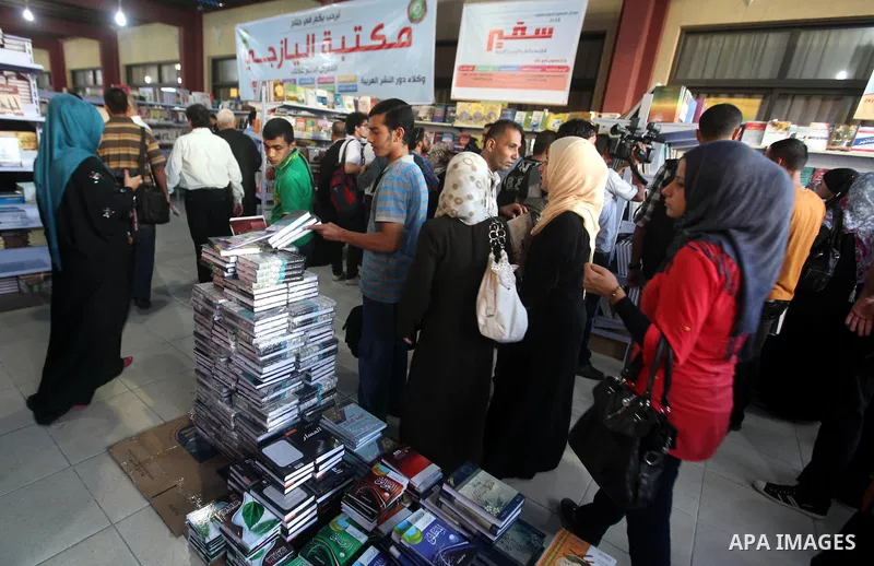 Palestinian visitors read books at a booth during the launch of the International Book Fair Exhibition, in Gaza city , Oct. 03, 2012. The Gaza International Book Fair has participated with more than 70 publishers from Pa...