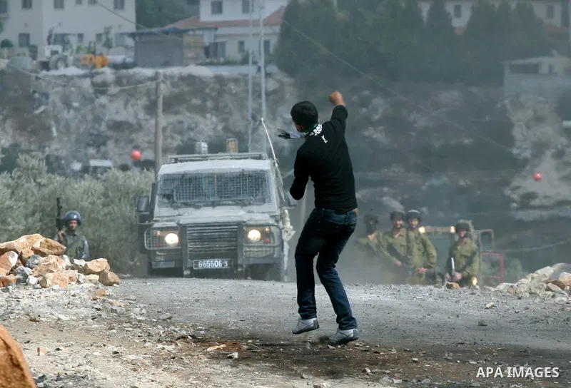 A Palestinian protester throws stones at Israeli soliders during clashes following a demonstration against the expropriation of Palestinian land by Israel in the village of Kafr Qadum in the occupied West Bank on October...