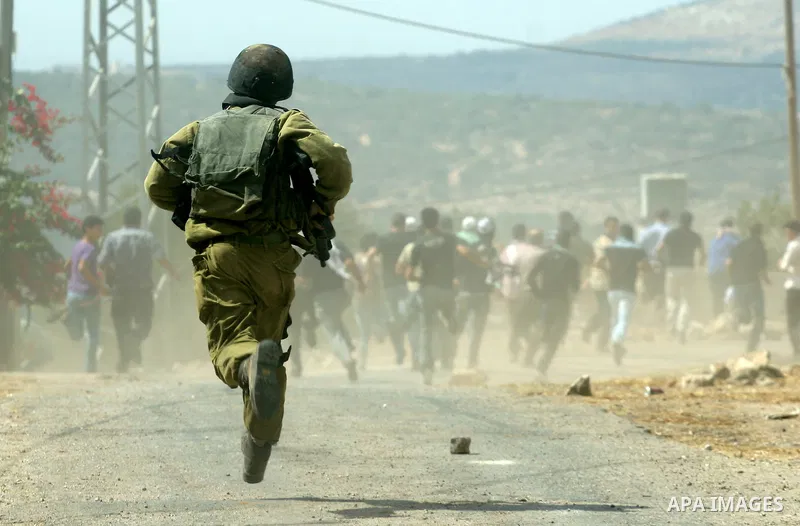 An Israeli soldier runs after Palestinian and foreign protesters during clashes following a demonstration against the expropriation of Palestinian land by Israel in the village of Kafr Qadum in the occupied West Bank on...