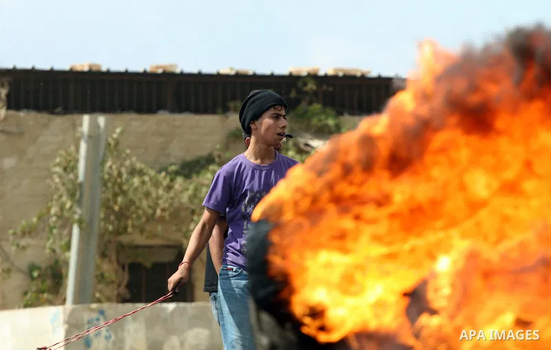 A Palestinian protester uses a sling shot to hurl stons at Israeli soldiers during clashes following a demonstration against the expropriation of Palestinian land by Israel in the village of Kafr Qadum in the occupied We...