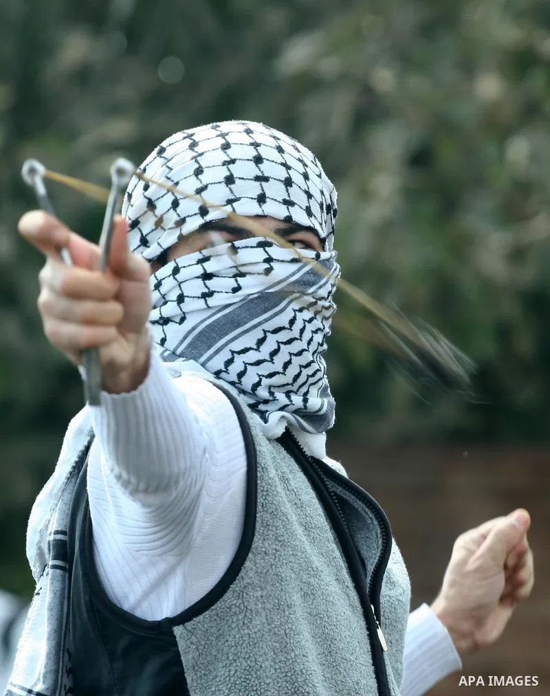 A masked Palestinian protester uses a sling shot to hurl stons at Israeli soldiers during clashes following a demonstration against the expropriation of Palestinian land by Israel in the village of Kafr Qadum in the occu...