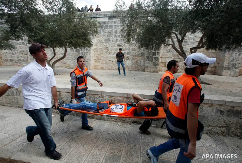 Palestinian medics carry a wounded worshipper during clashes at the Al Aqsa Mosque compound, known by the Jews as the Temple Mount, in Jerusalem's Old City, Friday, Oct. 5, 2012. Earlier this week, hardline Jewish activi...