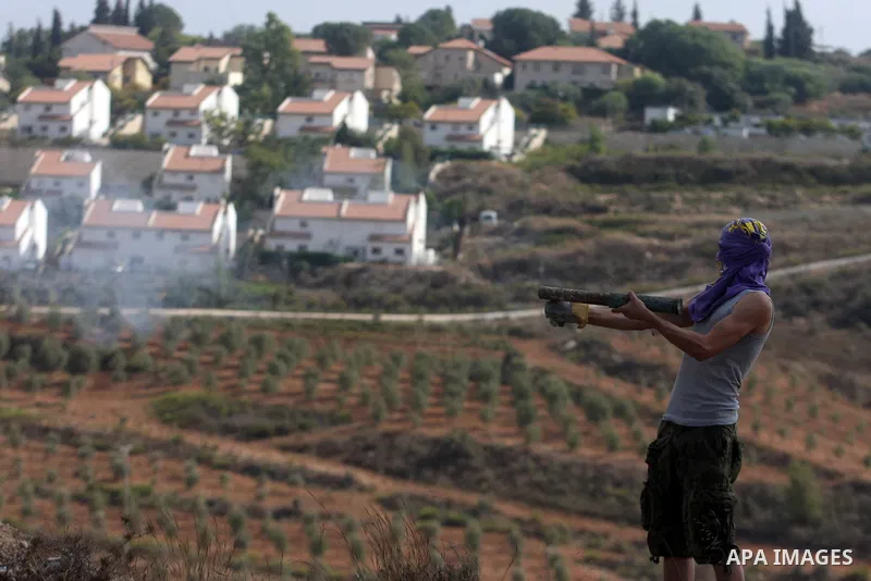 A Palestinian protester carries a primitive weapon during a weekly protest against the expansion of the nearby Jewish settlement of Halamish, in the West Bank village of Nabi Saleh near Ramallah, Friday, Oct 5, 2012. Pho...