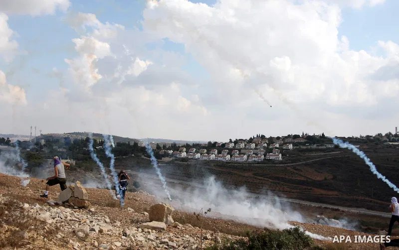 A Palestinian protester runs from tear gas during a weekly protest against the expansion of the nearby Jewish settlement of Halamish, in the West Bank village of Nabi Saleh near Ramallah, Friday, Oct 5, 2012. Photo by Is...