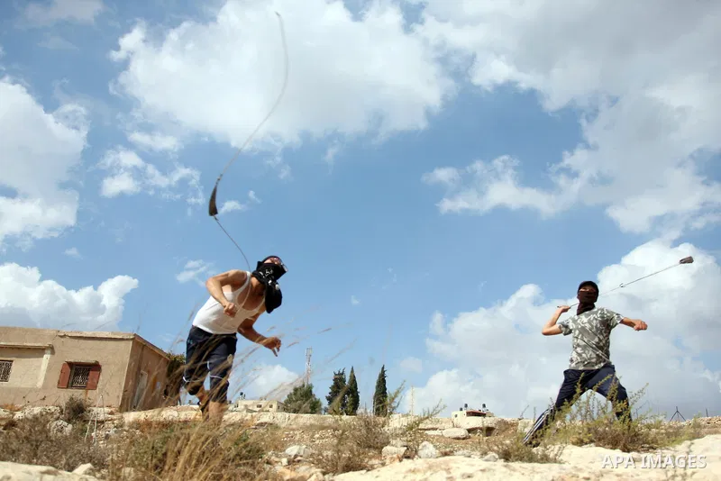 Palestinian protester hurl stones at Israeli soldiers, not seen, during a weekly protest against the expansion of the nearby Jewish settlement of Halamish, in the West Bank village of Nabi Saleh near Ramallah, Friday, Oc...