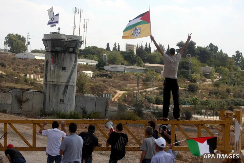 Palestinian demonstrators hold a national flags during a weekly protest against the expansion of the nearby Jewish settlement of Halamish, in the West Bank village of Nabi Saleh near Ramallah, Friday, Oct 5, 2012. Photo...