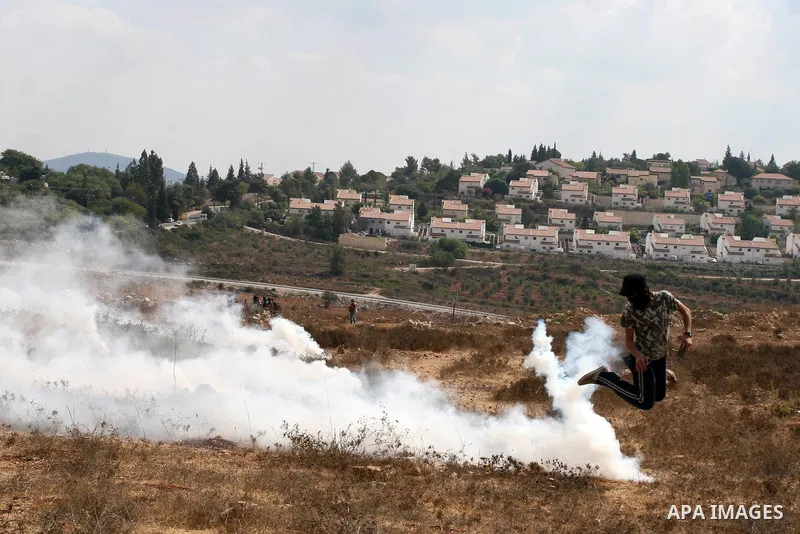 A Palestinian protester runs from tear gas during a weekly protest against the expansion of the nearby Jewish settlement of Halamish, in the West Bank village of Nabi Saleh near Ramallah, Friday, Oct 5, 2012. Photo by Is...